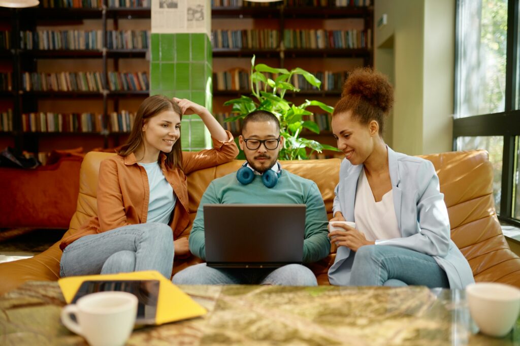 Employee shows teammates business solutions on laptop screen at coworking space