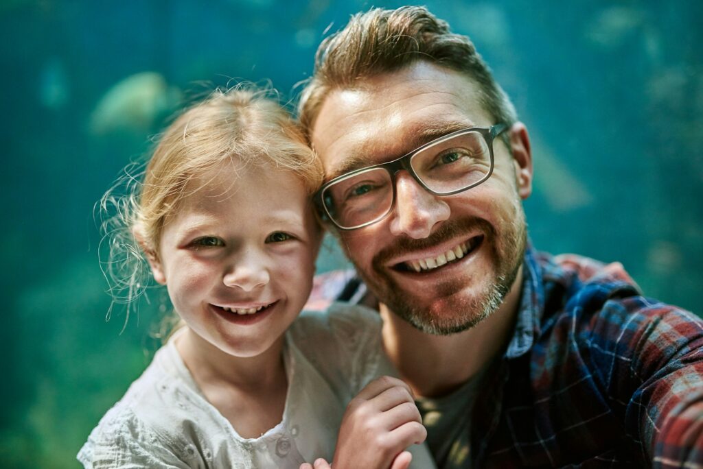 Portrait of a father and his little daughter taking a selfie together at an aquarium